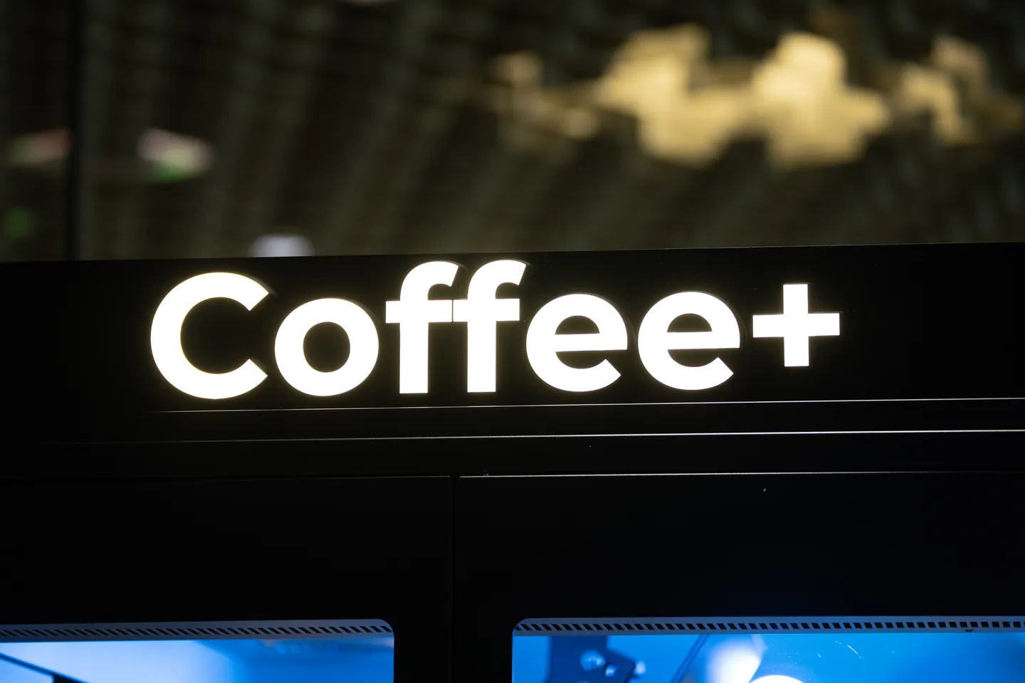 Der leuchtende Coffee+ Schriftzug am schwarzen Gehäuse der Anlage.
